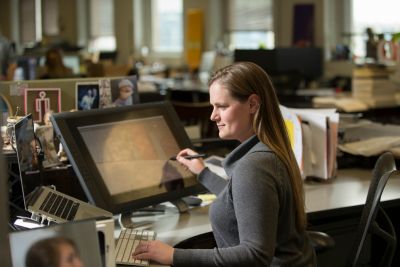 woman working at a desk on a large monitor